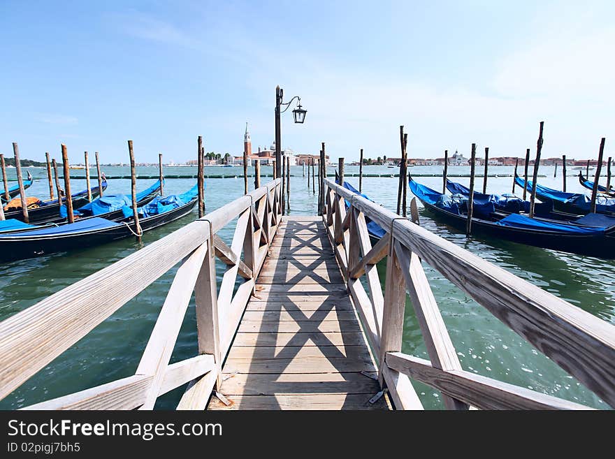 A row of gondola boats anchored along the Grand Canal in Venice, Italy. A row of gondola boats anchored along the Grand Canal in Venice, Italy.