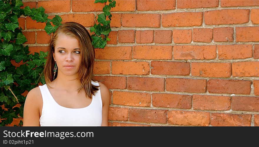 Attractive teen posing against a brick wall on a warm summer day.