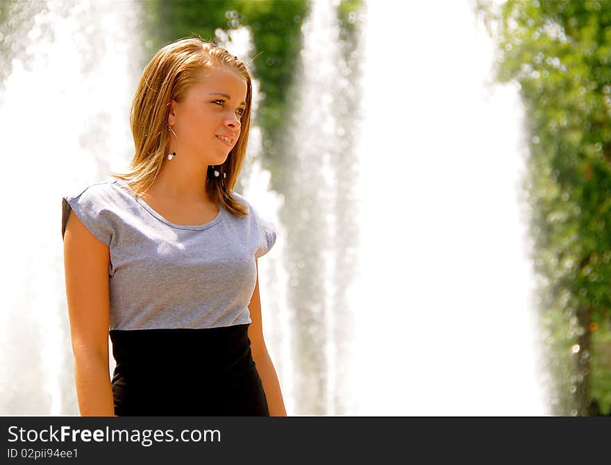 Attractive teen girl in front of a fountain on a hot summer day.