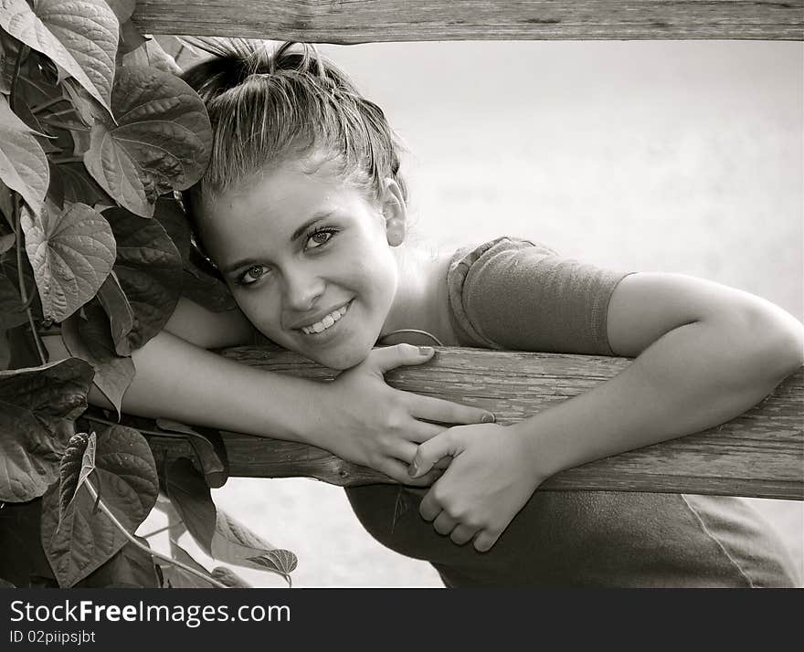 Beautiful teen girl posing on a garden fence at a nearby park.