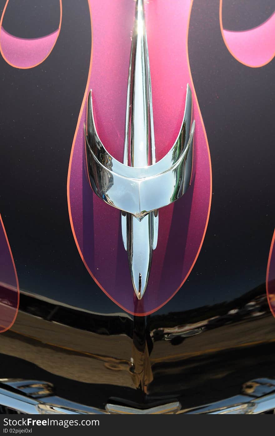 Detail of chrome hood ornament with pink flames. Detail of chrome hood ornament with pink flames