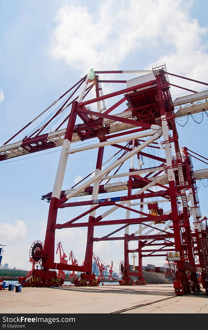 Rows of shipping containers, with a large crane overhead, lifting more containers into place. Rows of shipping containers, with a large crane overhead, lifting more containers into place