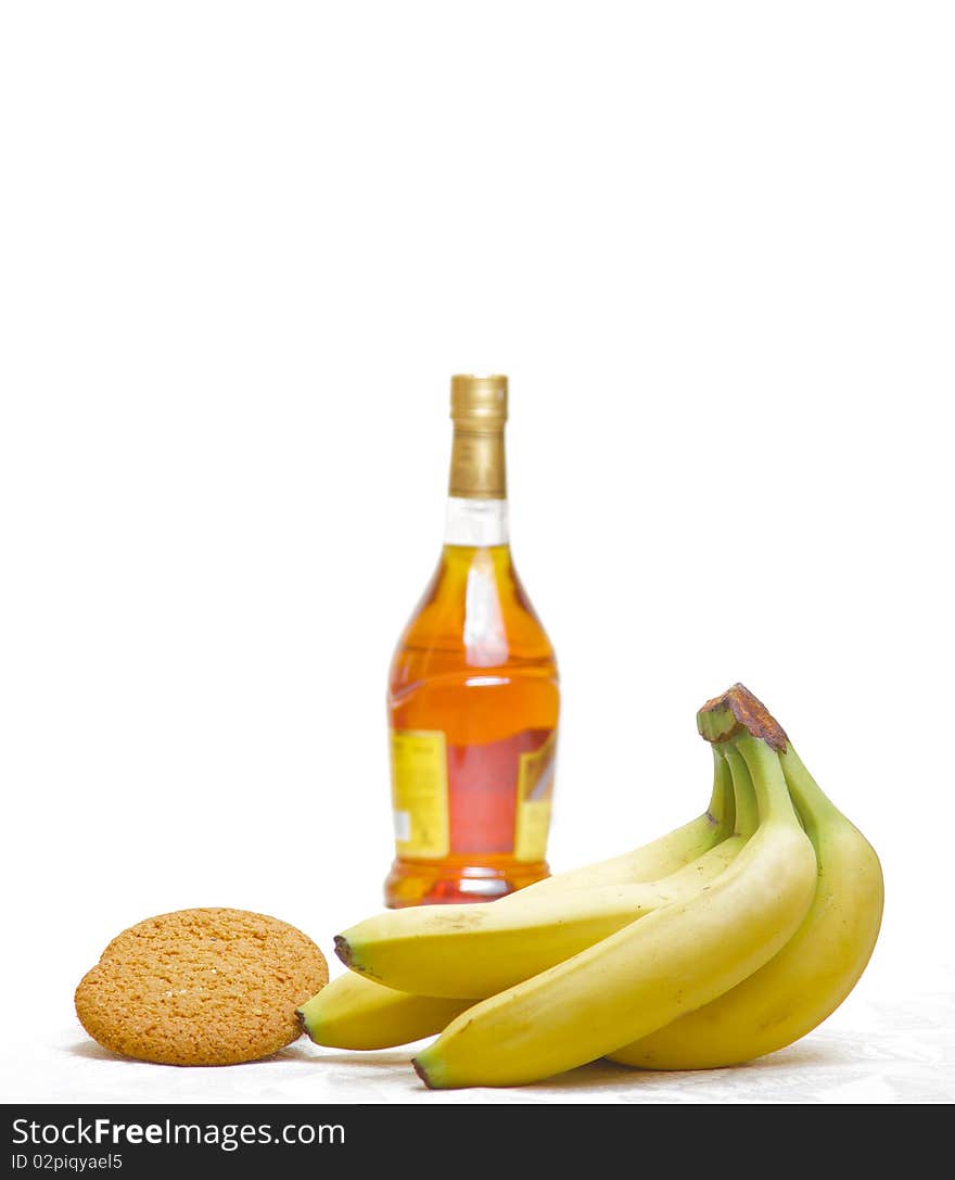 Bottle of  brandy, yellow banana and cookie isolated. Bottle of  brandy, yellow banana and cookie isolated