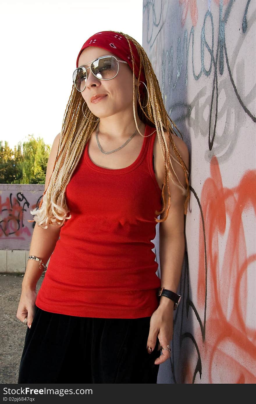 Fashionable hip-hop chick posing outdoors at graffiti sprayed wall. Fashionable hip-hop chick posing outdoors at graffiti sprayed wall