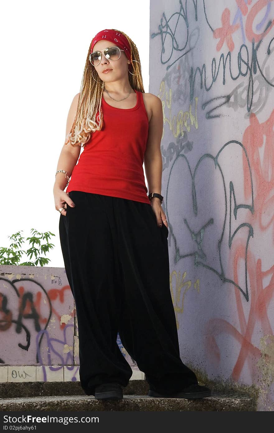 Teenage rapper girl standing outdoors at graffiti sprayed wall. Teenage rapper girl standing outdoors at graffiti sprayed wall