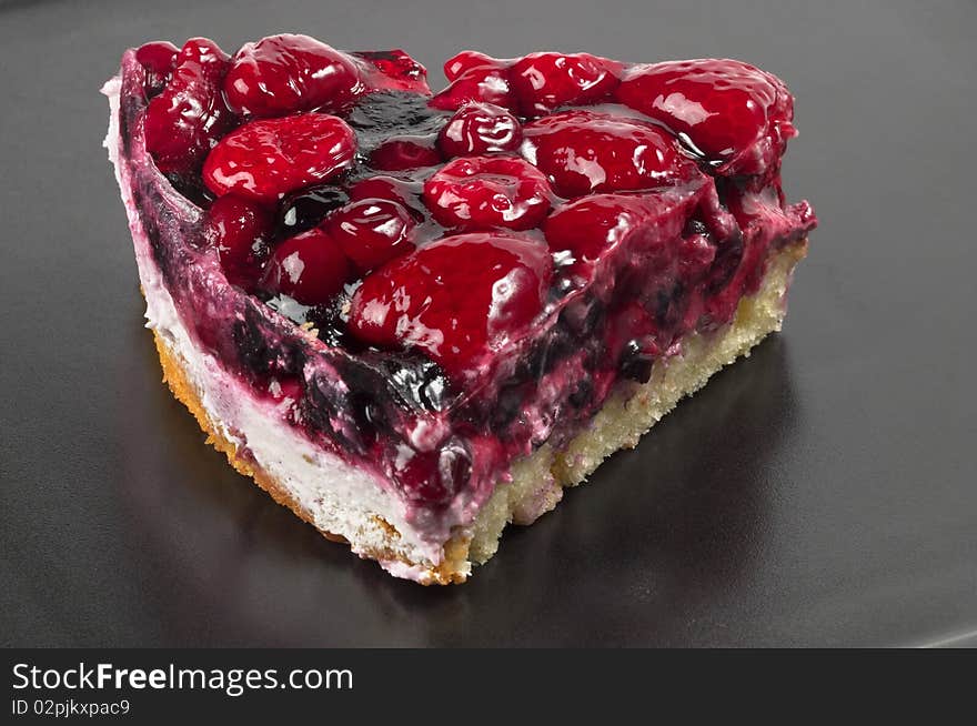 Small berries tart piece macro shot over black background