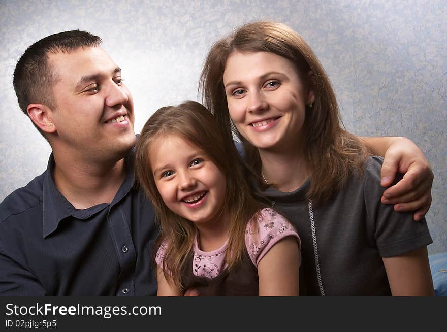 Young mother, father, and daughter over light defocused background. Young mother, father, and daughter over light defocused background