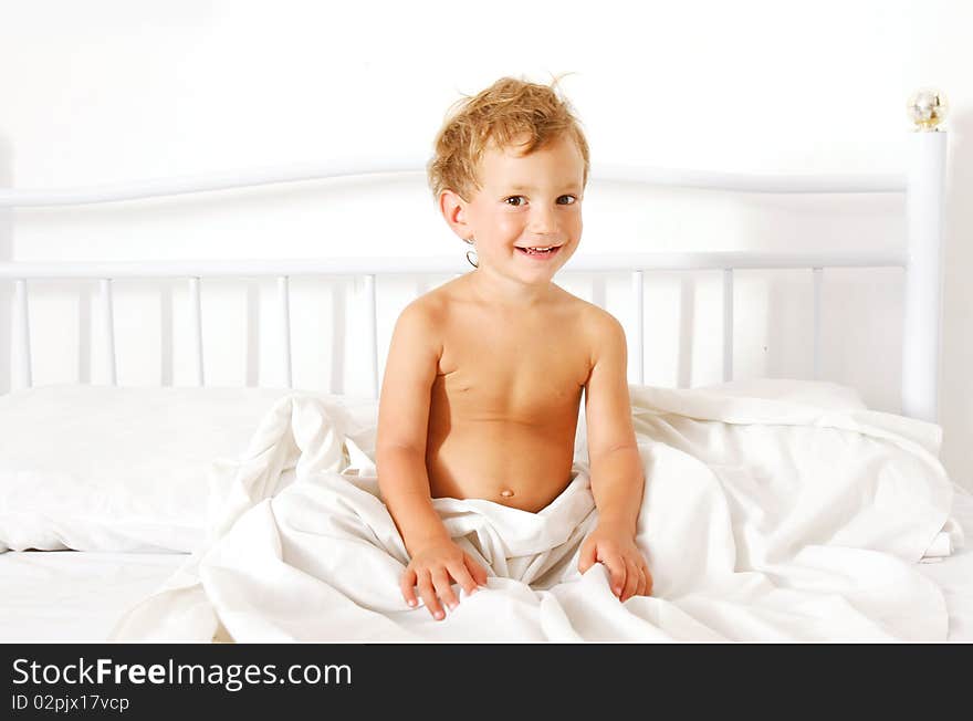 Smiling boy sitting in bed. Smiling boy sitting in bed