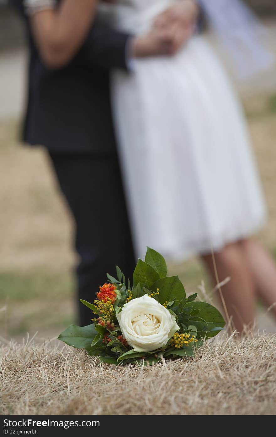 Wedding bouquet with rose on the ground - wedding couple in background