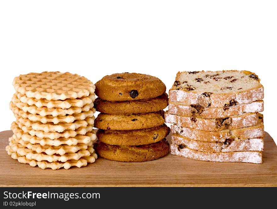 Piles of wafers, oatmeal biscuits and cake on wooden board, isolated