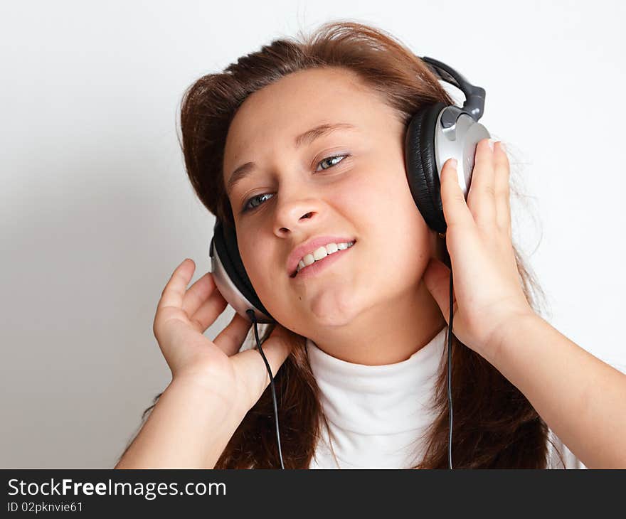 Beautiful girl with headphones on a light background