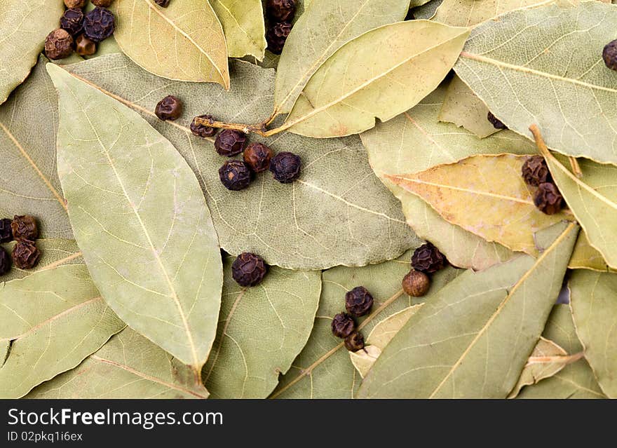 Background of bay leaves and black peppercorns