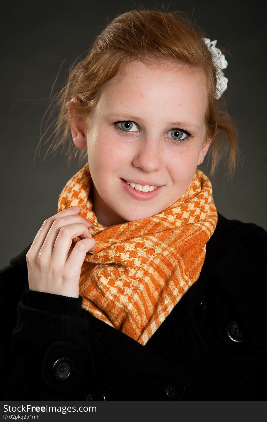 Beautiful teen girl with scarf in front of dark green background