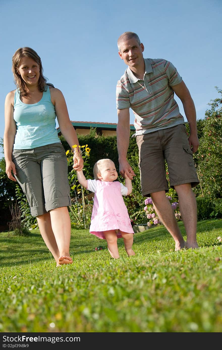 Young family walking in the garden of their home. Young family walking in the garden of their home