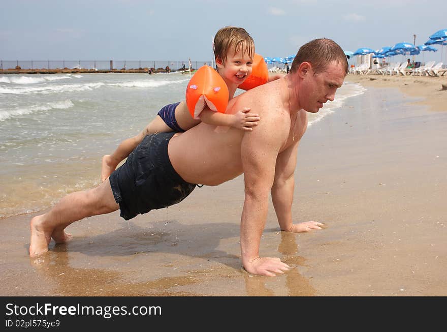 Father is in the fitness on the beach with his son. Father is in the fitness on the beach with his son