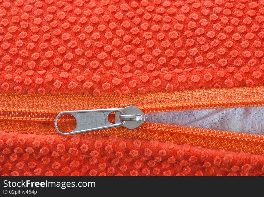 Studio shot of orange zipper, halfway open.