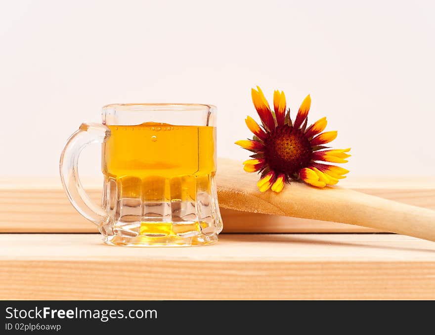 Honey in a small mug on wood with a wooden spoon and flower. Honey in a small mug on wood with a wooden spoon and flower