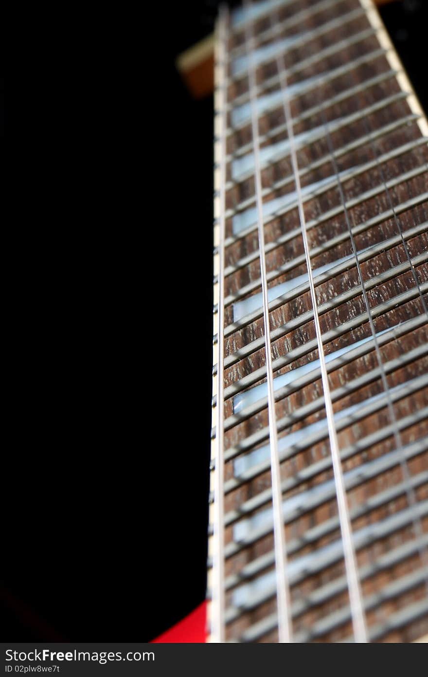 A six string electric guitar isolated on a black background.