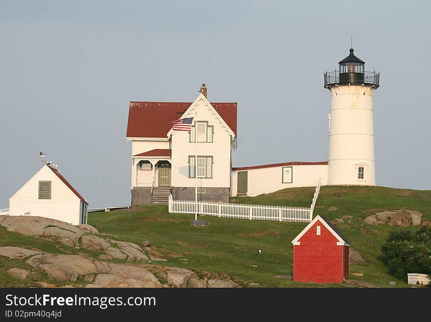 Sunset on Nubble Lighthouse considered to be the most photographed lighthouse. It's conical tower is 41' tall and it sits on a small off shore rocky islet in York,Maine. Tower, Keepers house and boat house.