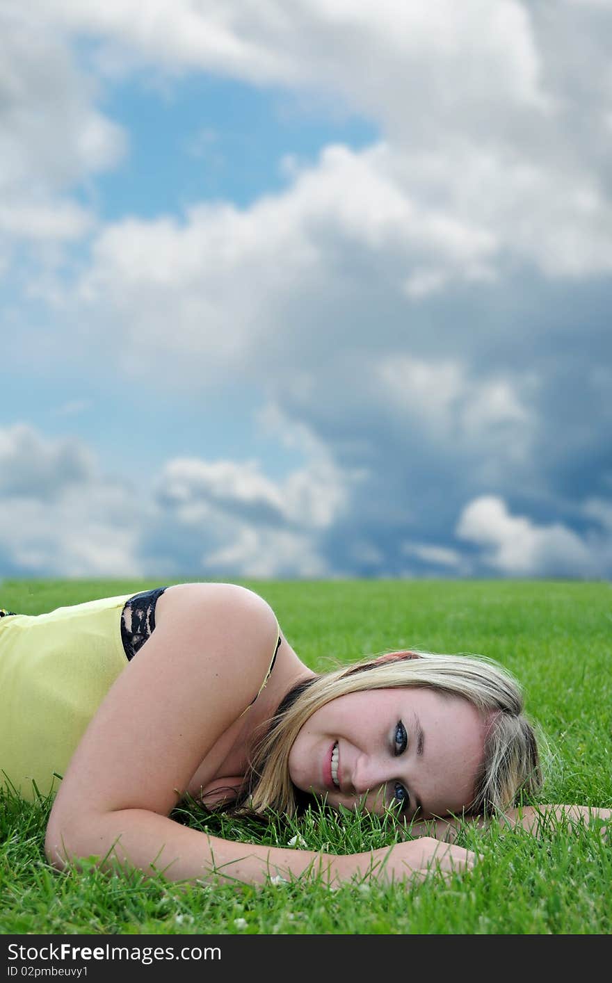 Closeup of a beautiful blond white Caucasian young adult teenage girl laying in a green grass field smiling at the camera. Closeup of a beautiful blond white Caucasian young adult teenage girl laying in a green grass field smiling at the camera.