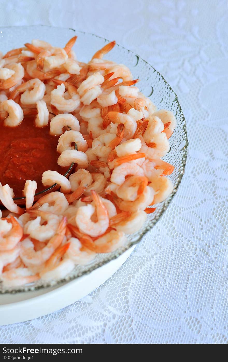 A bunch of shrimp arranged in a bowl with red sweet sauce for dip. A bunch of shrimp arranged in a bowl with red sweet sauce for dip.