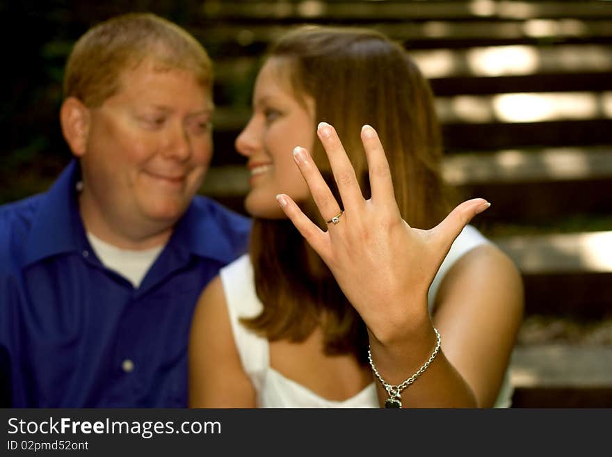 A couple in love series shot in the woods. The engaged young woman is proudly showing off her engagement ring. A couple in love series shot in the woods. The engaged young woman is proudly showing off her engagement ring.