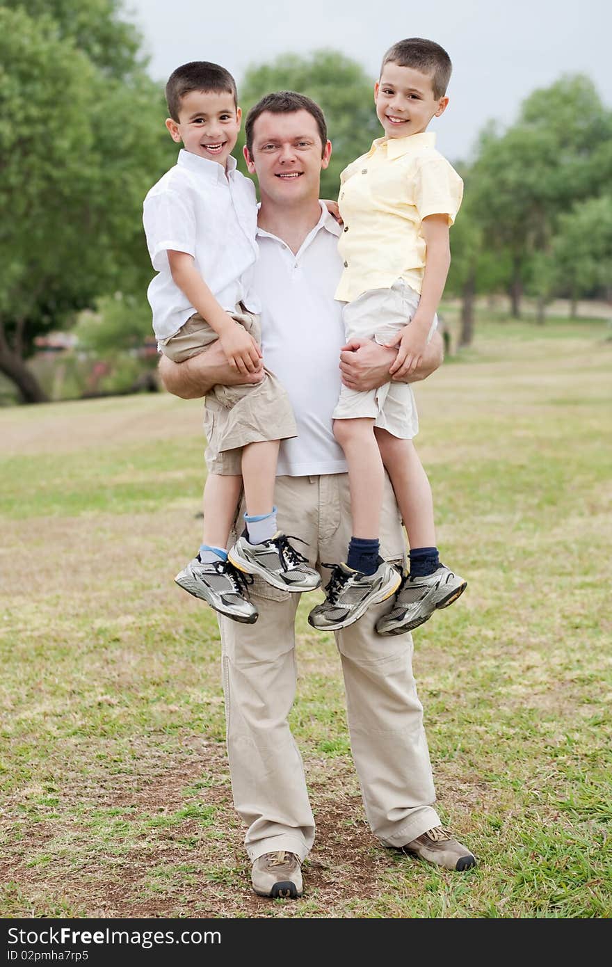 Father carrying his two sons in his hands on a natural background. Father carrying his two sons in his hands on a natural background