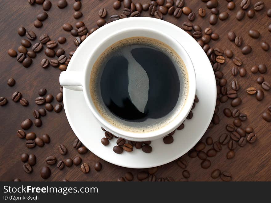 A cup of hot coffee on the table with coffee beans