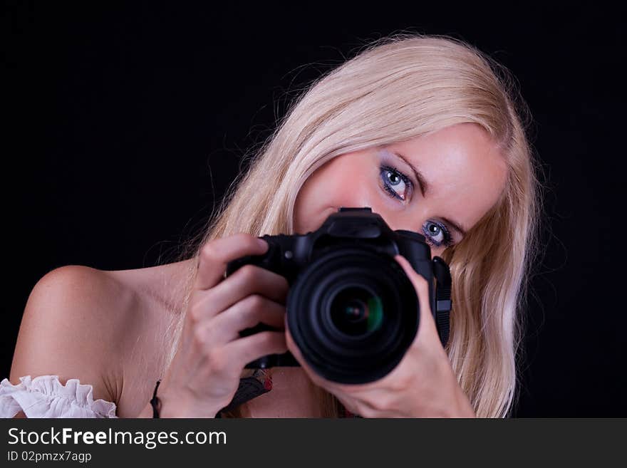 Blonde hair woman, holding camera aimed in front of you. Black Background. Blonde hair woman, holding camera aimed in front of you. Black Background.