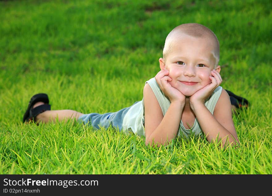 Cheerful child lying on green grass and smiling. Cheerful child lying on green grass and smiling