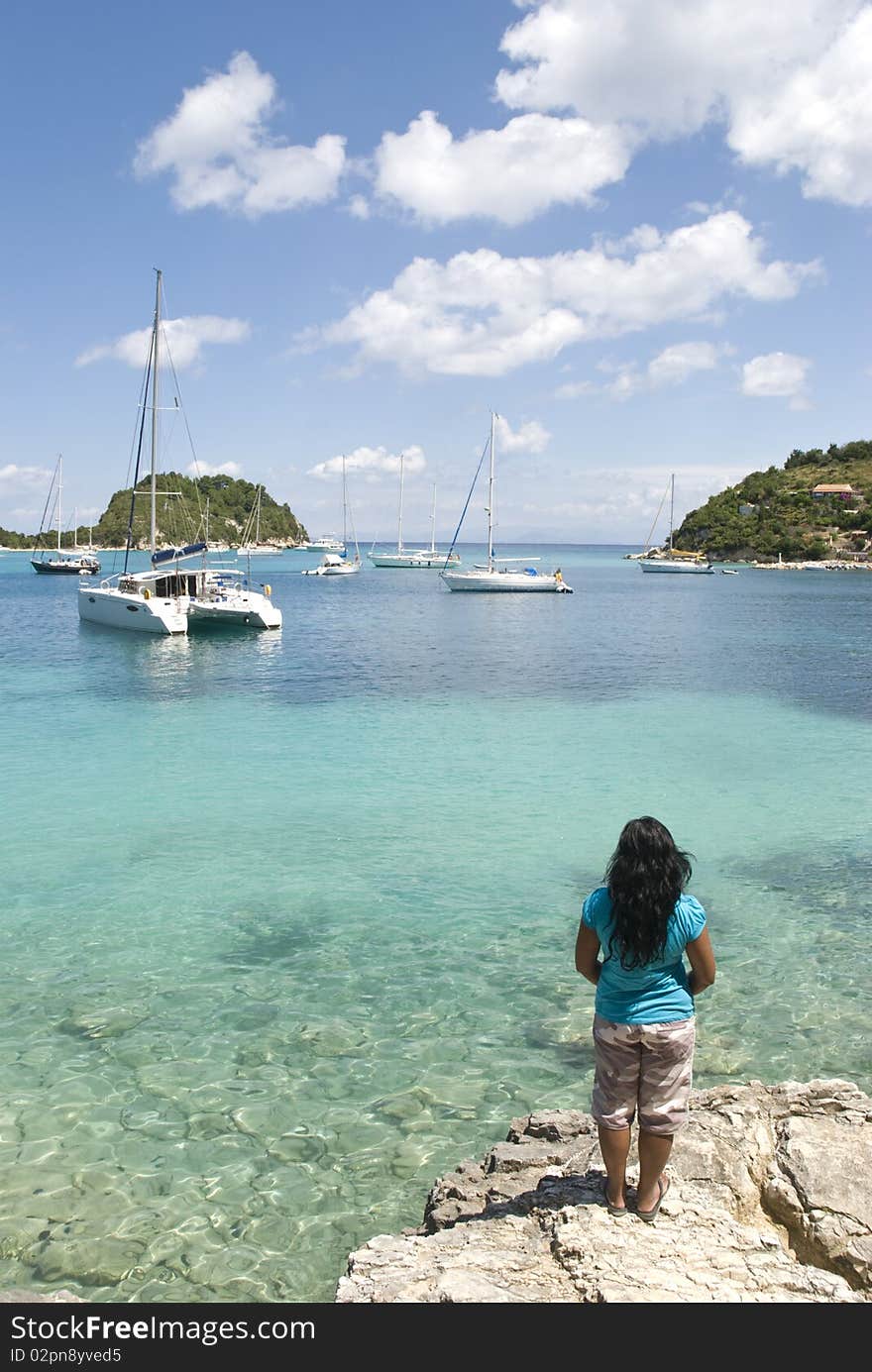 A color portrait photo of a dark haired womanstanding on a rock and enjoying the view of Lakka Harbour in Paxos Greece. A color portrait photo of a dark haired womanstanding on a rock and enjoying the view of Lakka Harbour in Paxos Greece.