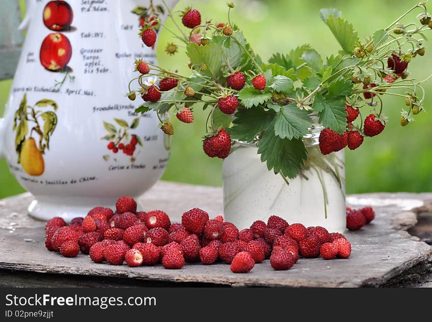 Sprigs with a strawberry stand in a glass jar, the mineral deposit of strawberry lies alongside