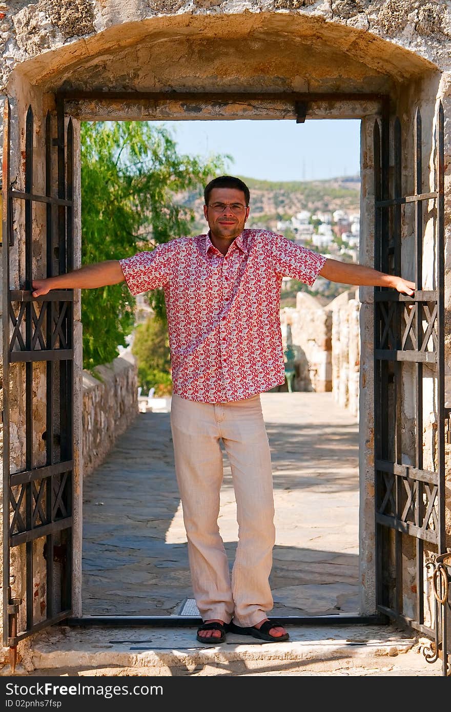 A man with open arms standing in a doorway of old castle. A man with open arms standing in a doorway of old castle