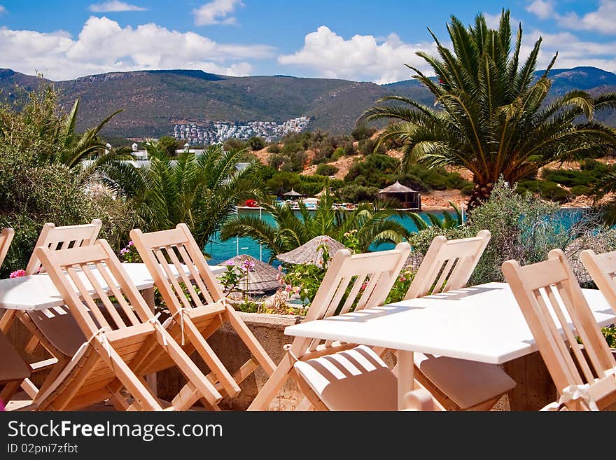 Beautiful view of a restaurant near the sea, with palms and mountains