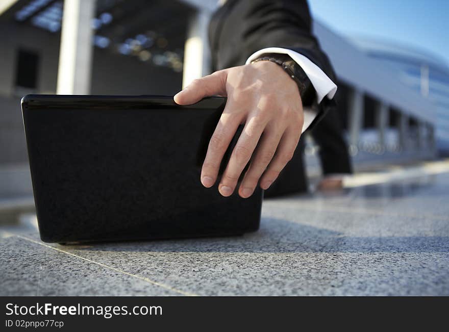 Businessman closing a laptop on the street