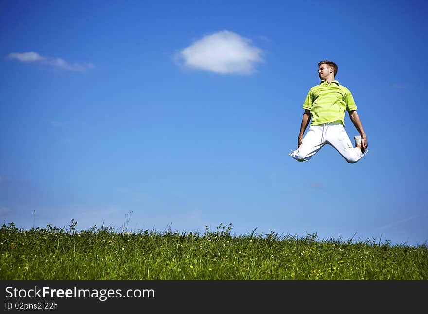 Jumping Up Guy In A Green Shirt Against Blue Sky.