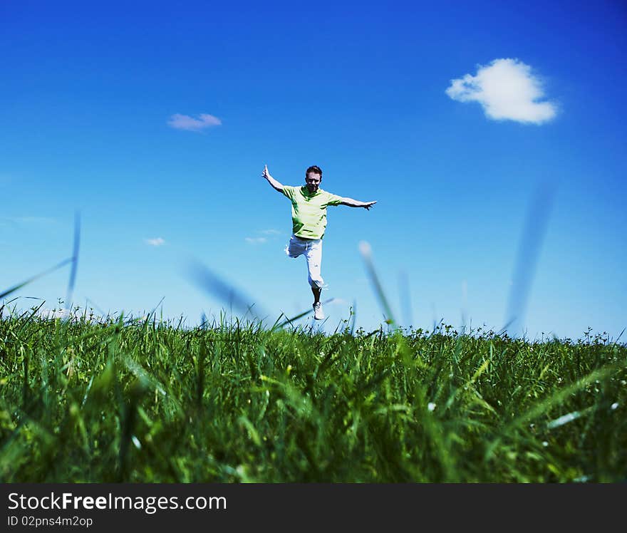 Jumping Up Guy In A Green Shirt Against Blue Sky.