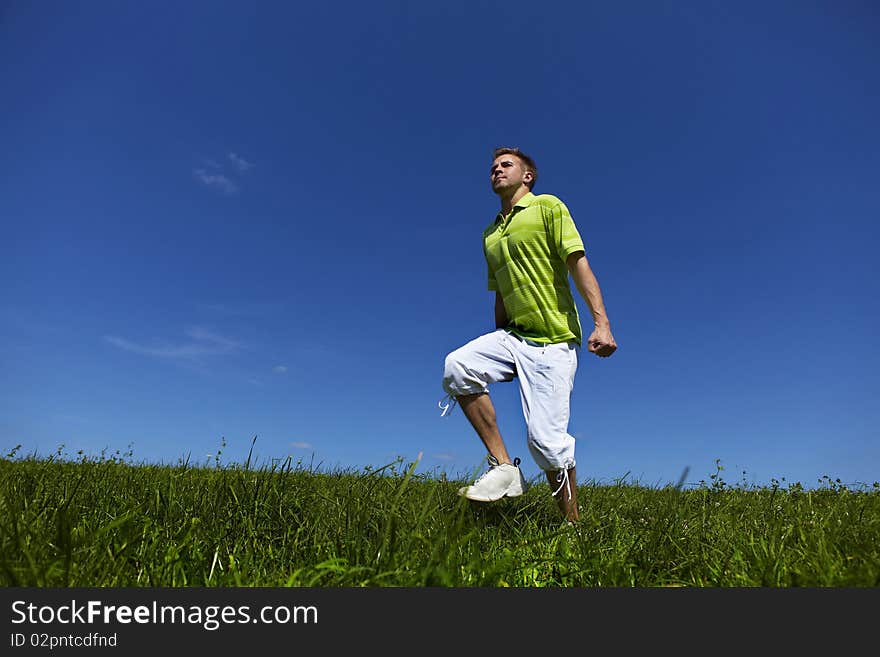 Jumping up guy in a green shirt against blue sky. photo