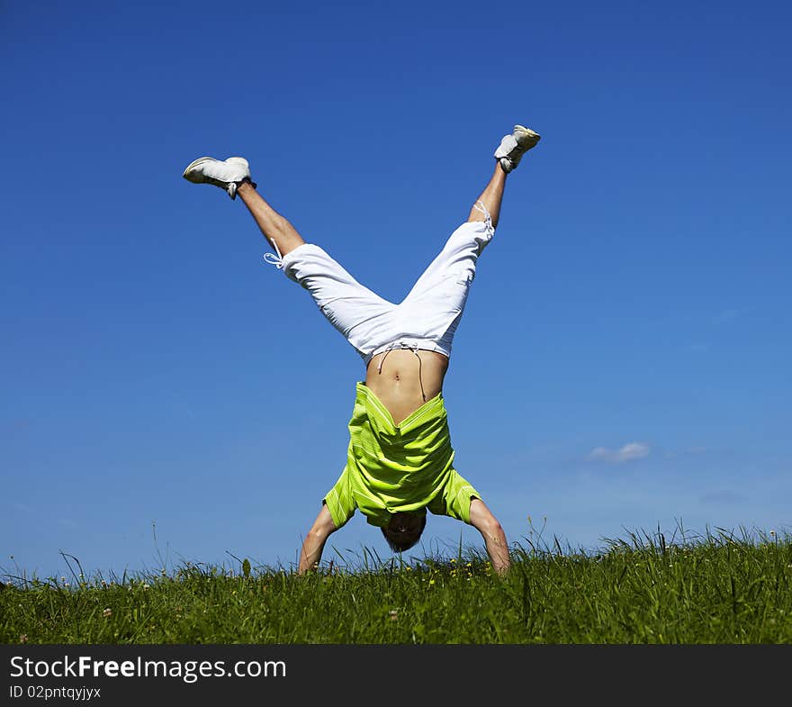 Jumping Up Guy In A Green Shirt Against Blue Sky.