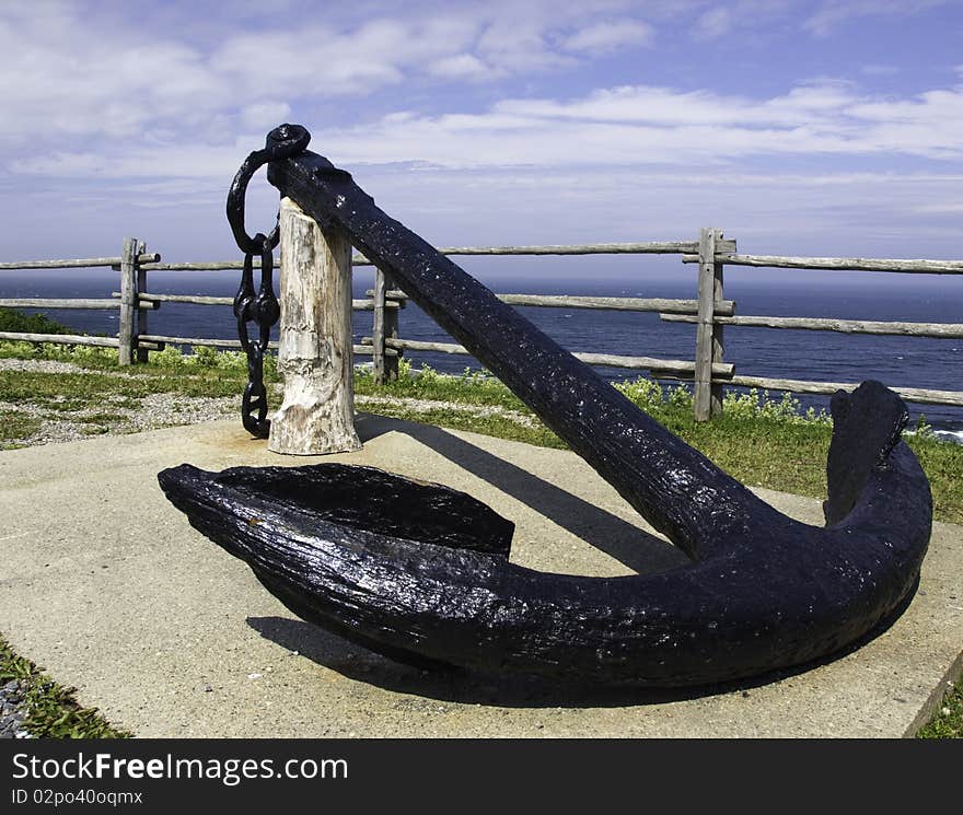 Old black anchor on display in front of the ocean