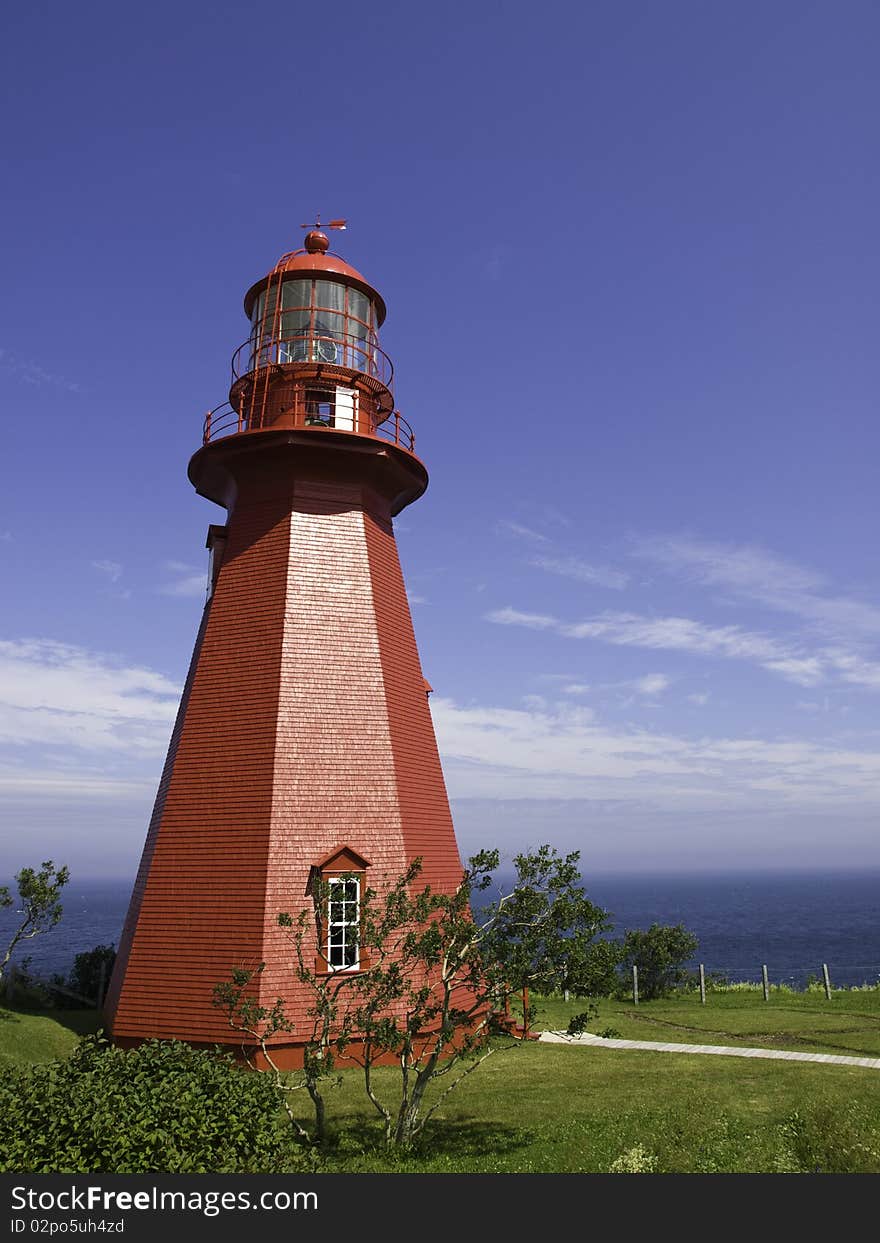 Old wooden red lighthouse standing in front of the ocean