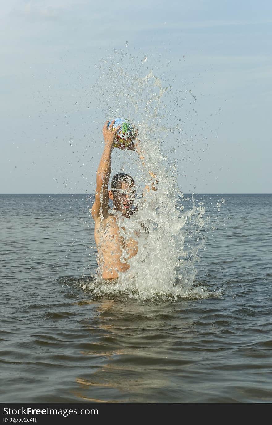 Man playing with a ball on the water, vertical photo. Man playing with a ball on the water, vertical photo.