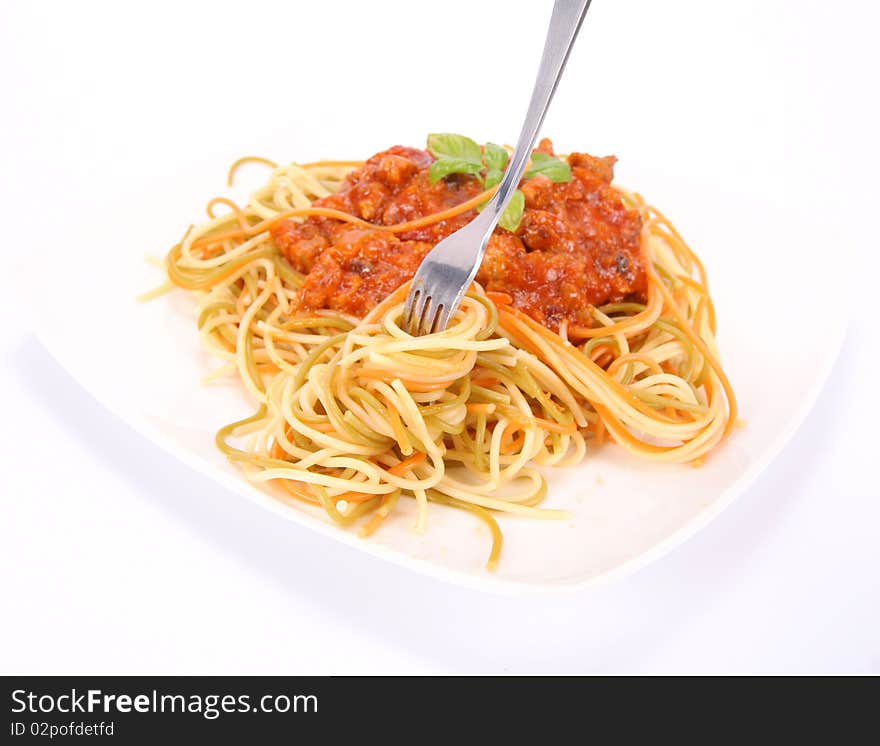 Colorful spaghetti bolognese on a plate being eaten with a fork