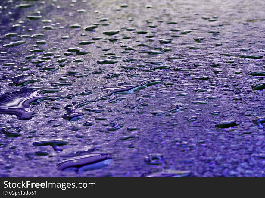 a background of blue glass with drops of water on it which are reflecting the light. a background of blue glass with drops of water on it which are reflecting the light