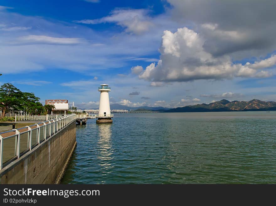 The sun shine, white lighthouse in the water, reflecting scenery and charming, In front of the mountain, is Hong Kong border