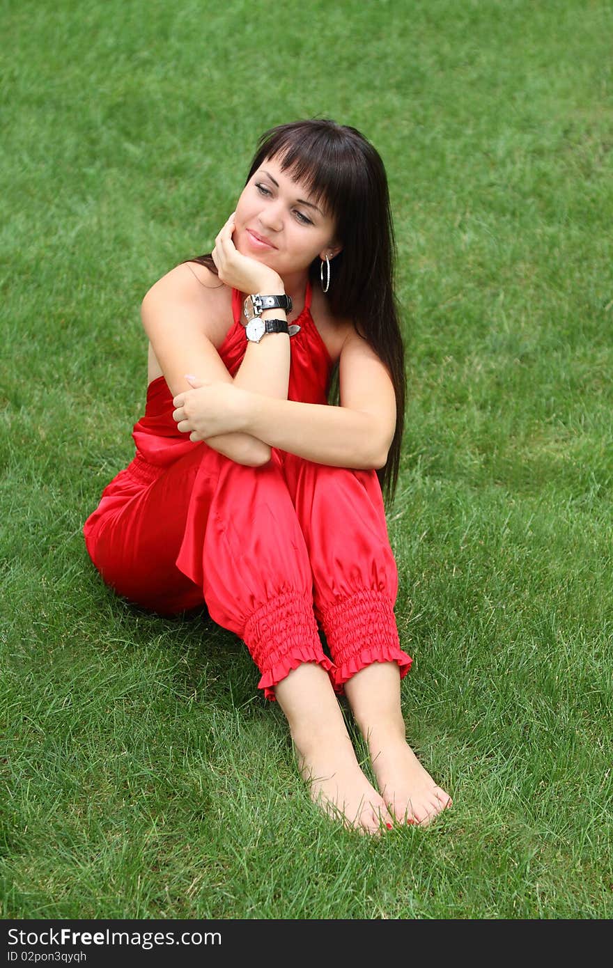 Brunette girl in red on the green grass. Brunette girl in red on the green grass