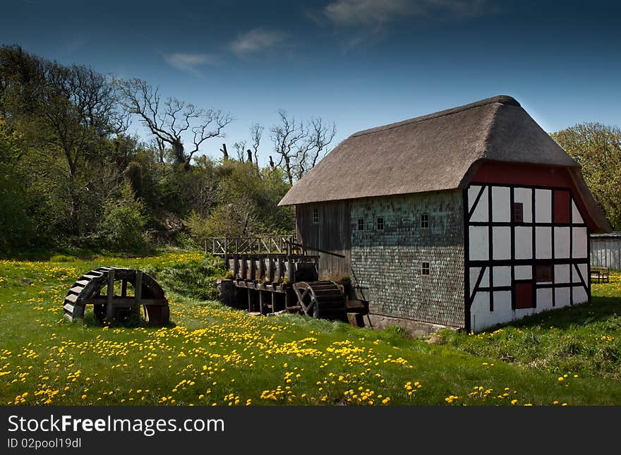 Vintage danish water mill captured on a sunny day with blue sky and flowers in the foreground. Vintage danish water mill captured on a sunny day with blue sky and flowers in the foreground.