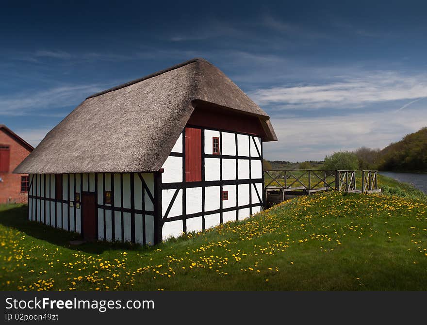 Vintage danish water mill captured on a sunny day with blue sky and flowers in the foreground. Vintage danish water mill captured on a sunny day with blue sky and flowers in the foreground.