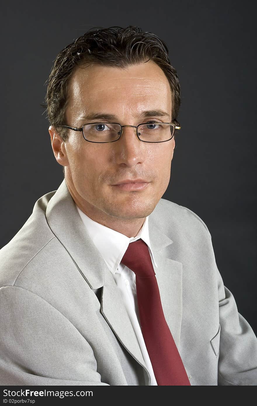 Man in grey jacket with red tie and glasses on grey background