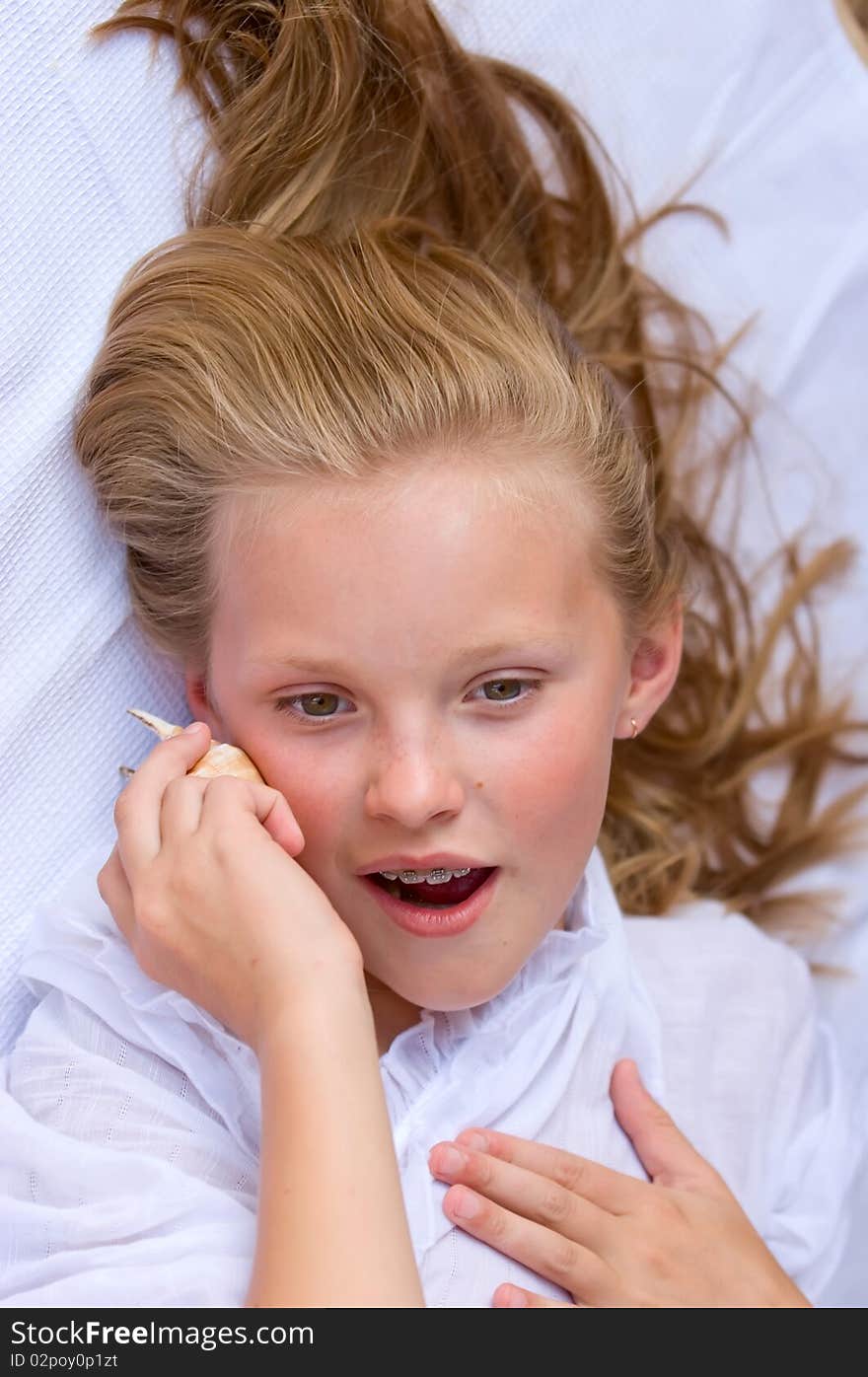 Beautiful young girl outdoor the cockleshell marine listens. Beautiful young girl outdoor the cockleshell marine listens